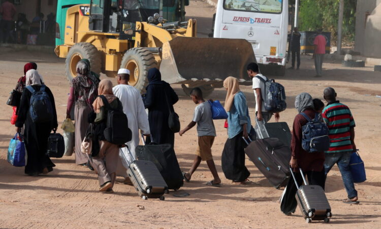 epa10635710 Sudanese people walk with belongings after crossing the border from Sudan, Abu Simbel, southern Egypt, 18 May 2023.  According to the UNHCR office, 83,758 Sudanese have crossed into Egypt since the beginning of an armed conflict on 15 April between the Sudanese military and the RSF (Rapid Support Forces) militia. The UN estimates some 200,000 people have fled Sudan since the conflict erupted  EPA-EFE/KHALED ELFIQI
